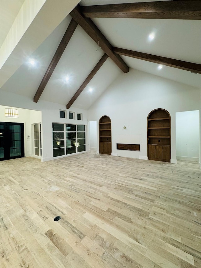 unfurnished living room featuring beamed ceiling, built in features, high vaulted ceiling, and light hardwood / wood-style flooring