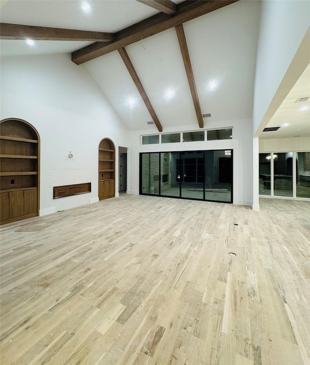 unfurnished living room with beam ceiling, high vaulted ceiling, and light wood-type flooring