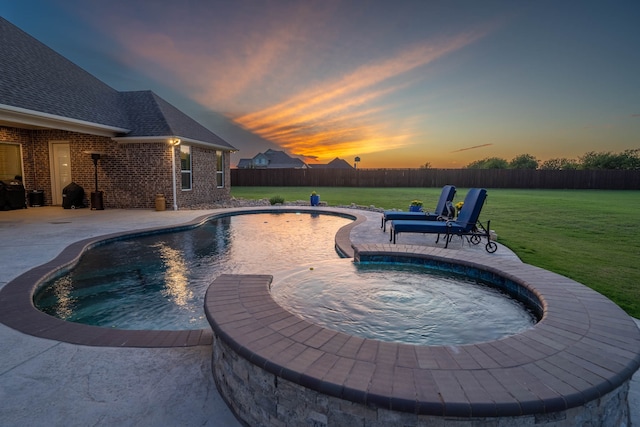 pool at dusk featuring a lawn and a patio