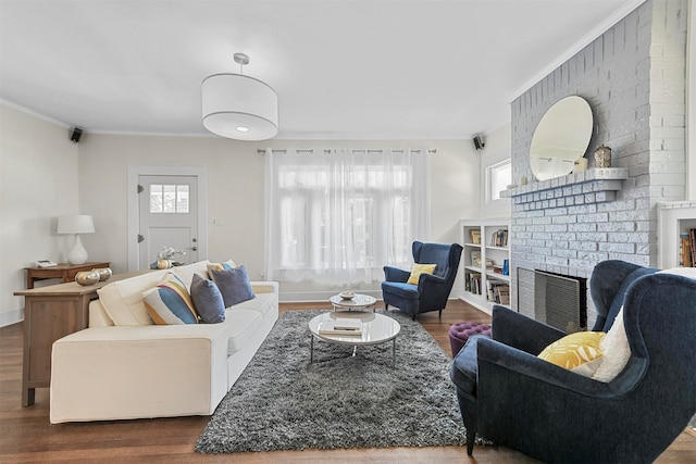 living room with brick wall, ornamental molding, hardwood / wood-style flooring, and a brick fireplace