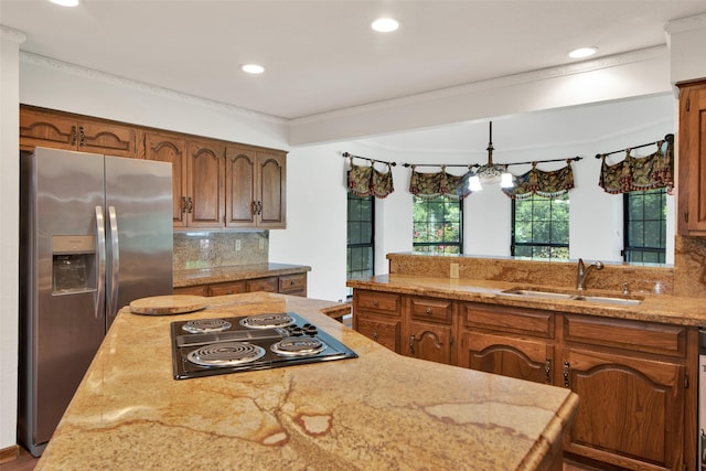 kitchen with backsplash, electric cooktop, sink, hanging light fixtures, and stainless steel fridge