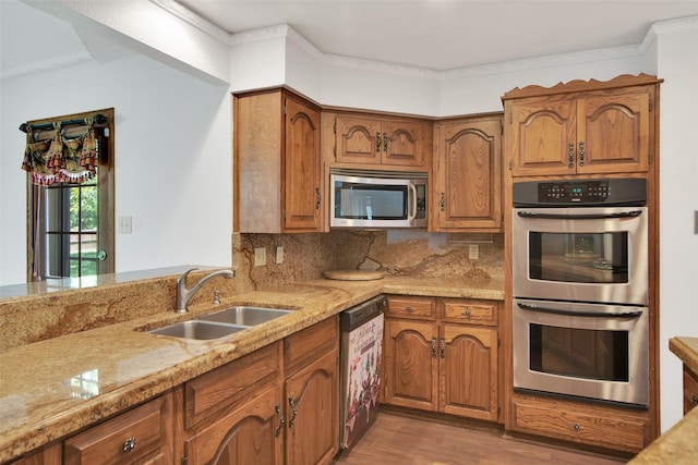 kitchen featuring sink, ornamental molding, appliances with stainless steel finishes, tasteful backsplash, and light stone counters