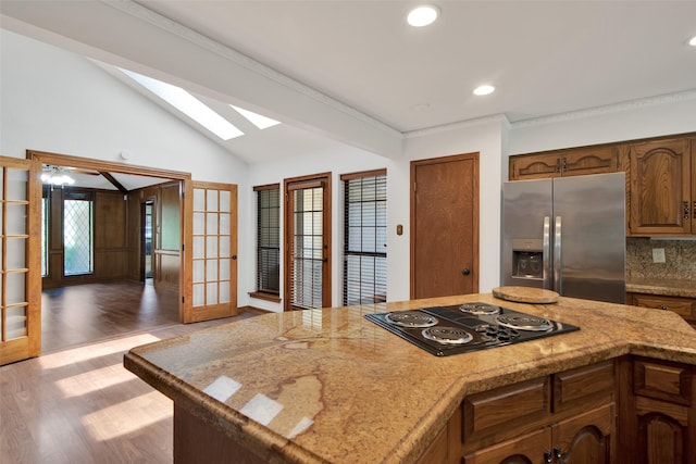 kitchen featuring decorative backsplash, stainless steel refrigerator with ice dispenser, french doors, black cooktop, and hardwood / wood-style flooring