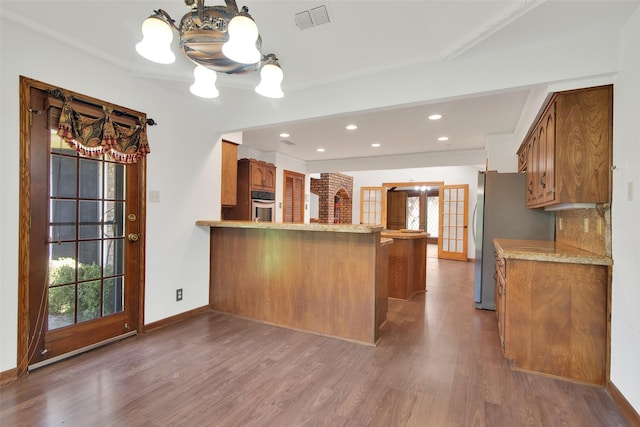 kitchen featuring kitchen peninsula, stainless steel appliances, tasteful backsplash, and dark hardwood / wood-style floors