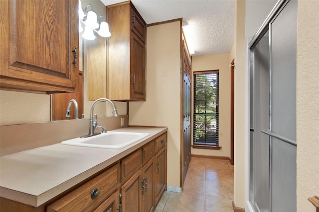 kitchen with light tile patterned flooring, a textured ceiling, and sink