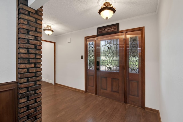 foyer with dark hardwood / wood-style flooring, ornamental molding, and a textured ceiling