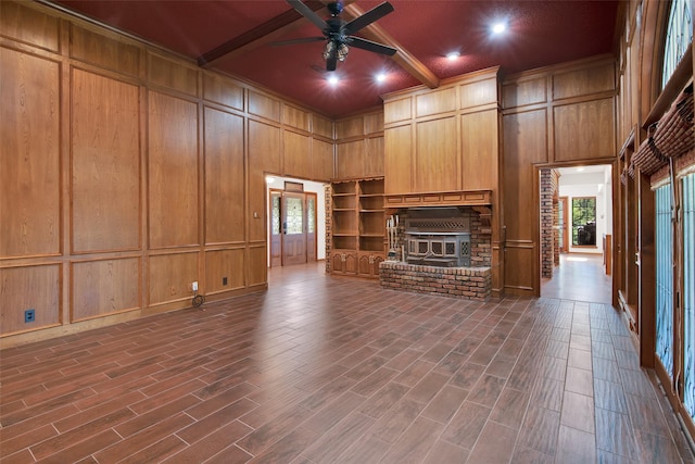 unfurnished living room featuring ceiling fan, coffered ceiling, beamed ceiling, a towering ceiling, and a fireplace