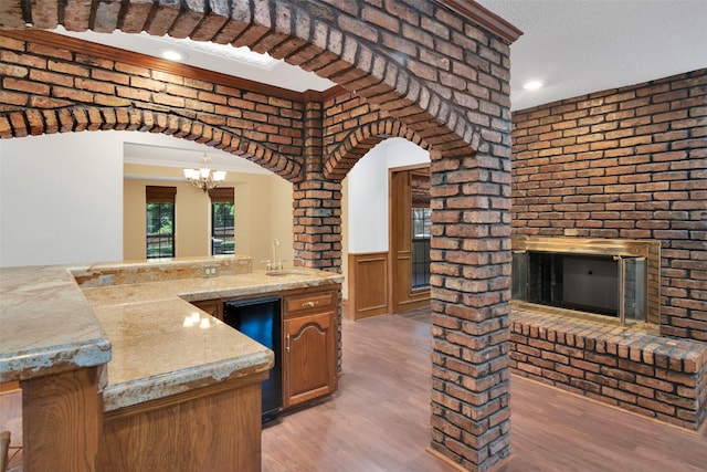 kitchen with brick wall, light hardwood / wood-style floors, crown molding, and sink