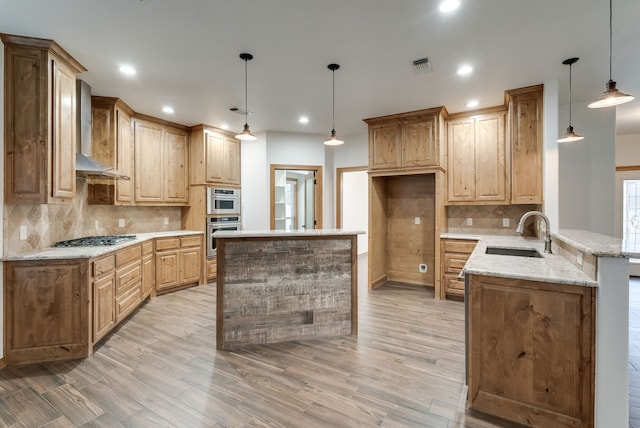 kitchen featuring light stone countertops, sink, kitchen peninsula, decorative light fixtures, and light wood-type flooring