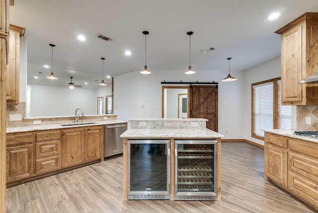 kitchen with appliances with stainless steel finishes, beverage cooler, sink, a barn door, and a kitchen island