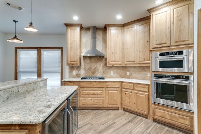 kitchen with decorative light fixtures, beverage cooler, wall chimney range hood, and light wood-type flooring