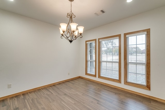 unfurnished room with a chandelier and hardwood / wood-style floors