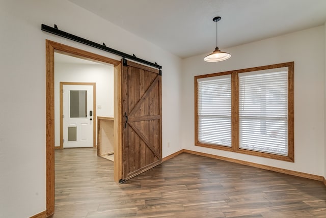 empty room featuring a barn door and dark hardwood / wood-style flooring