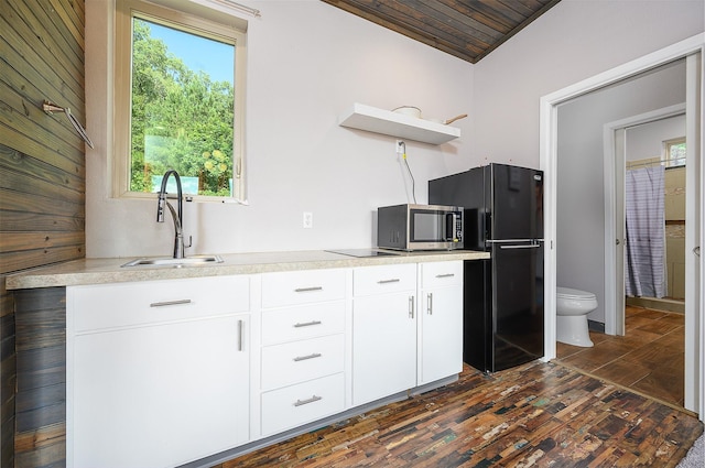 kitchen featuring black refrigerator, white cabinetry, sink, and a wealth of natural light