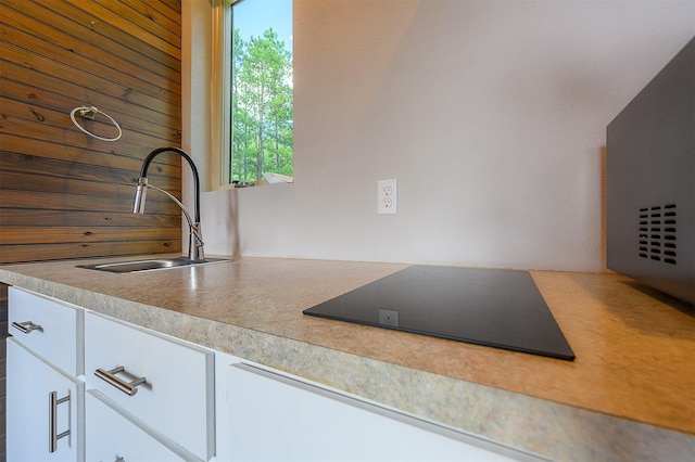 kitchen with white cabinetry, black electric cooktop, and sink