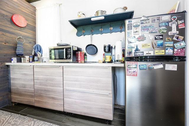 interior space with wood walls, dark tile patterned floors, and appliances with stainless steel finishes