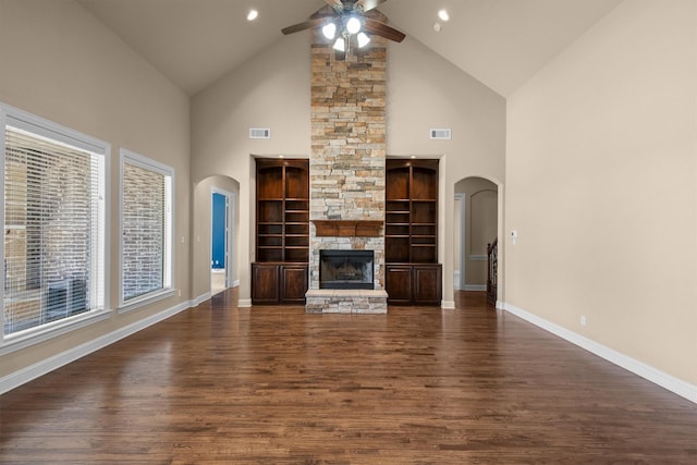 unfurnished living room featuring arched walkways, visible vents, a fireplace, and dark wood-type flooring