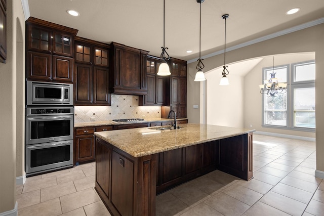 kitchen with light stone countertops, ornamental molding, a sink, appliances with stainless steel finishes, and backsplash