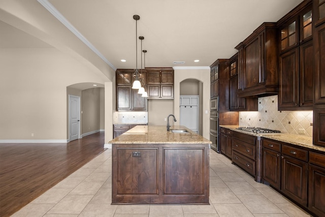 kitchen with arched walkways, glass insert cabinets, and a sink