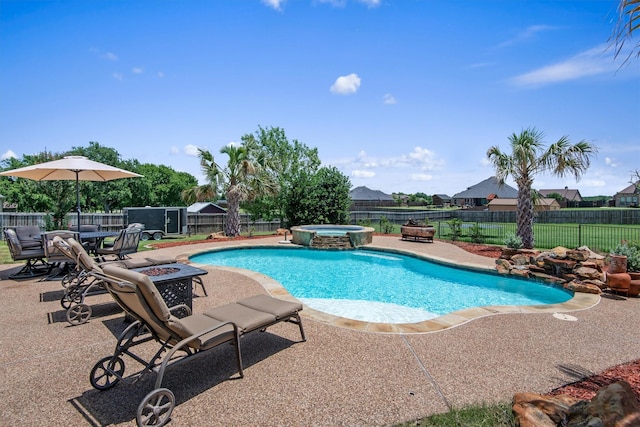 view of pool featuring a patio area, an outdoor fire pit, a pool with connected hot tub, and a fenced backyard