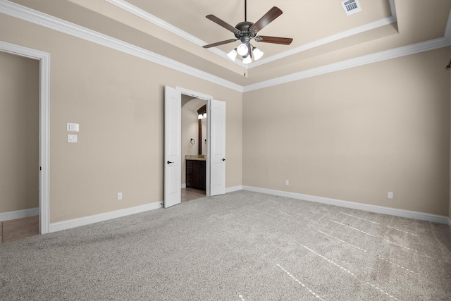 unfurnished bedroom with visible vents, baseboards, a tray ceiling, crown molding, and light colored carpet