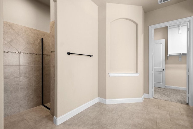 bathroom with baseboards, visible vents, and tiled shower