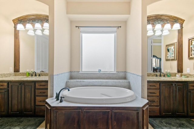 full bath with a sink, a garden tub, and two vanities