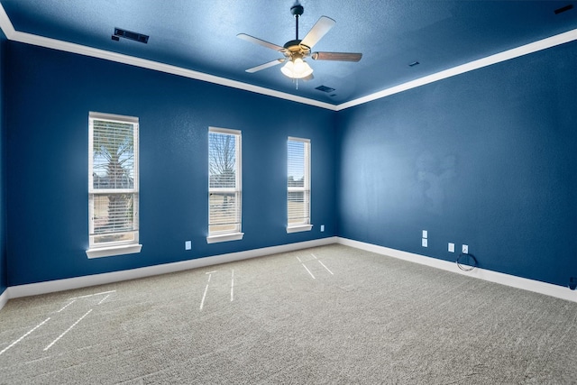 carpeted empty room with visible vents, a textured ceiling, a ceiling fan, and crown molding