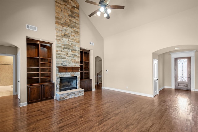 unfurnished living room featuring a stone fireplace, wood finished floors, visible vents, and baseboards