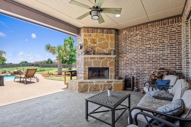 view of patio / terrace with an outdoor living space with a fireplace, a ceiling fan, and a fenced backyard