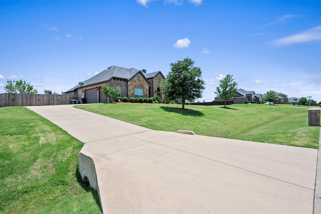 view of front of house featuring a front lawn, fence, concrete driveway, a garage, and stone siding