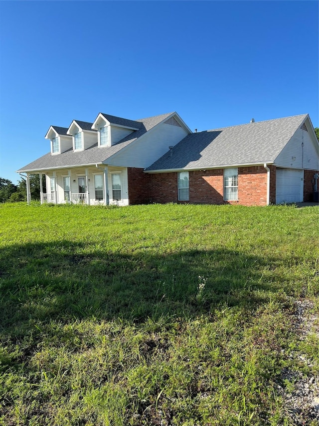 cape cod house with an attached garage, brick siding, and a front yard
