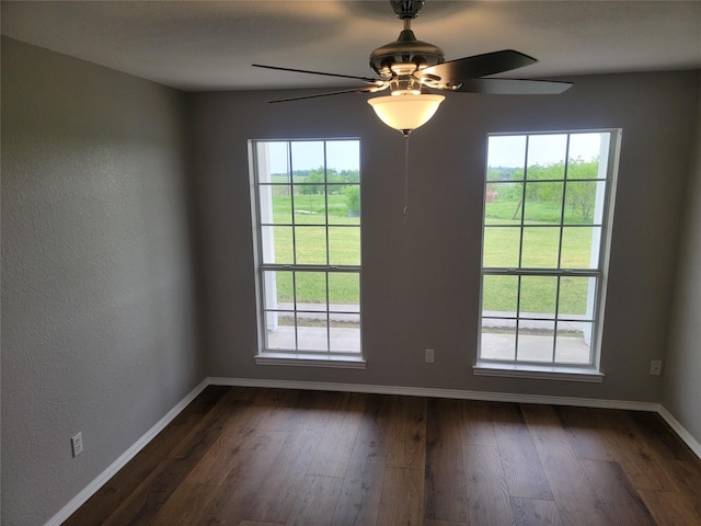 unfurnished room featuring ceiling fan, baseboards, dark wood-type flooring, and a wealth of natural light