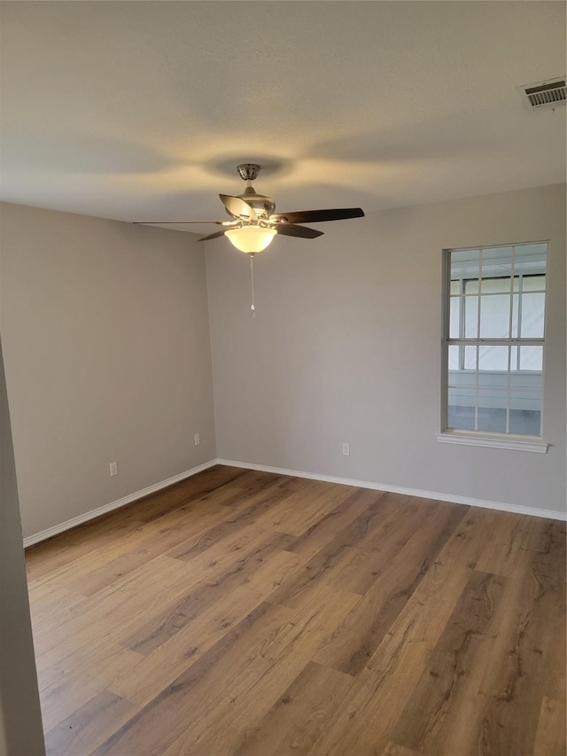 unfurnished room with baseboards, a ceiling fan, wood finished floors, and visible vents
