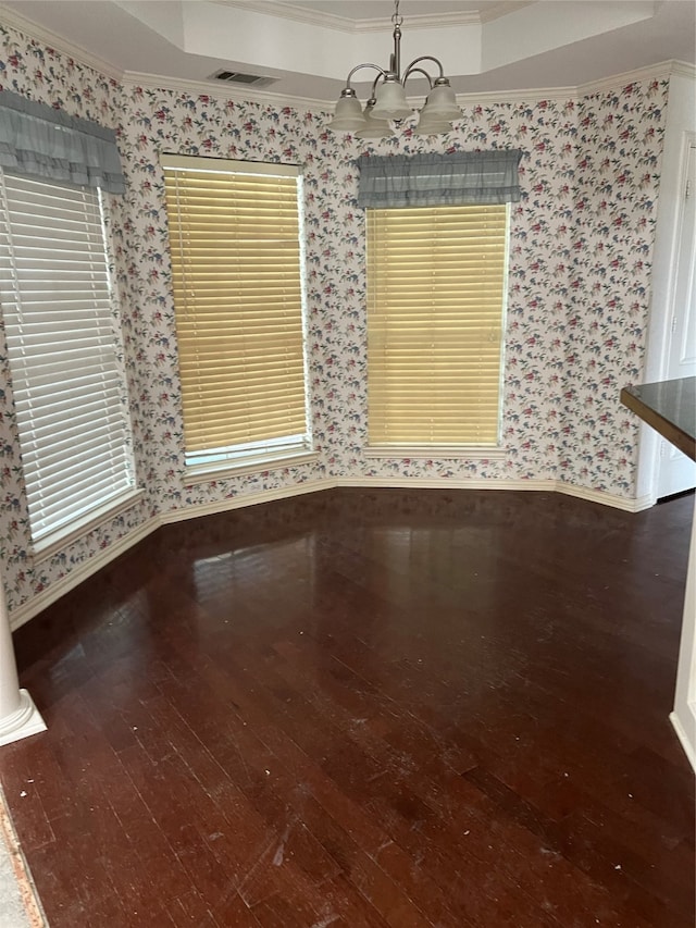 unfurnished dining area featuring a notable chandelier, a raised ceiling, dark hardwood / wood-style flooring, and ornamental molding