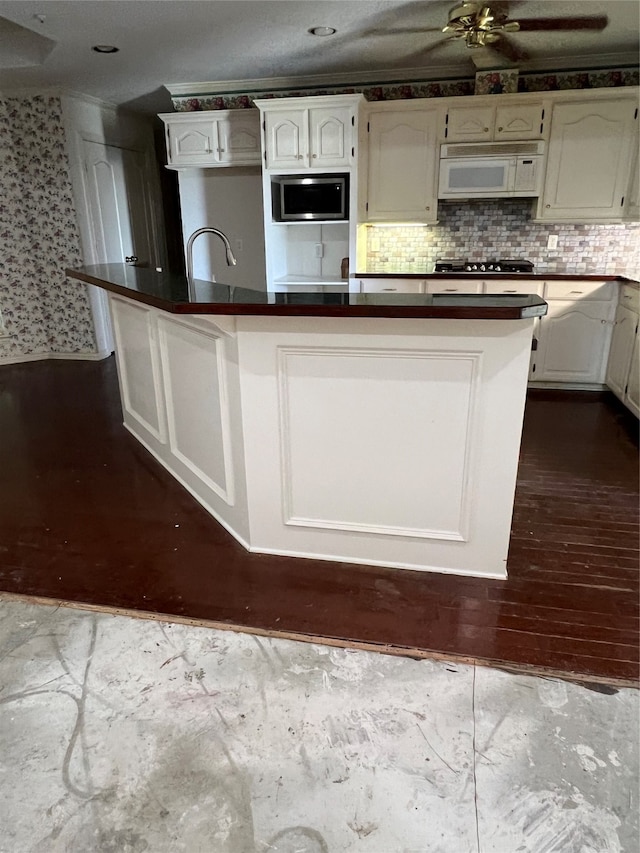 kitchen featuring ceiling fan, stainless steel microwave, backsplash, sink, and white cabinets