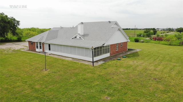 back of house with brick siding, a yard, a shingled roof, and a chimney