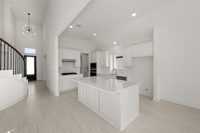 kitchen with dishwasher, sink, a notable chandelier, a kitchen island, and white cabinetry