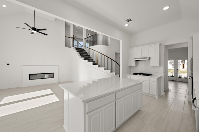 kitchen with gas cooktop, french doors, ceiling fan, white cabinets, and a kitchen island