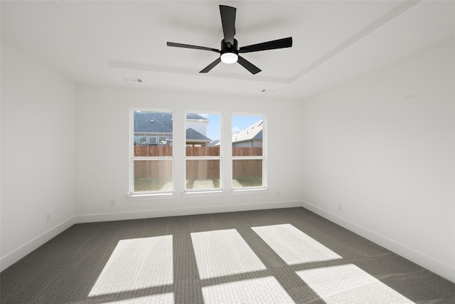 carpeted spare room featuring ceiling fan and a tray ceiling