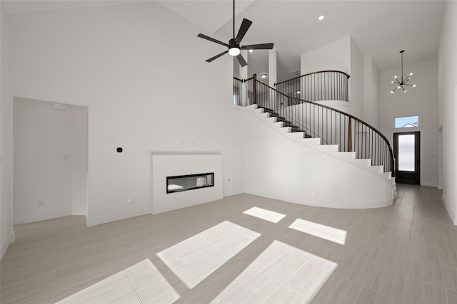 tiled living room with ceiling fan with notable chandelier and a towering ceiling