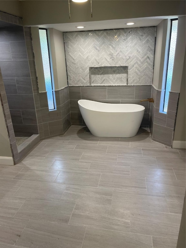 bathroom featuring separate shower and tub and tile walls