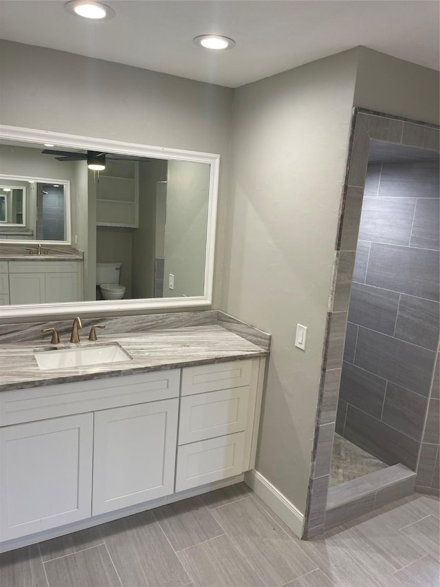 bathroom with vanity, toilet, and tiled shower