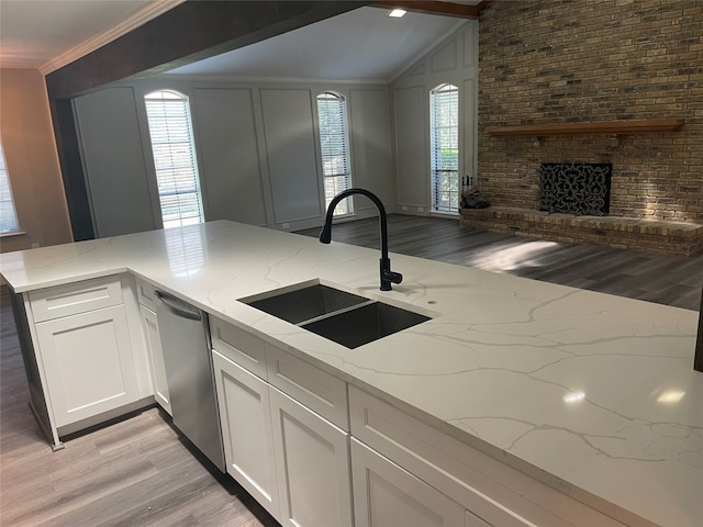 kitchen featuring dishwasher, white cabinets, sink, light stone countertops, and a fireplace