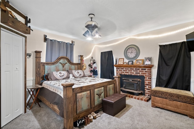 bedroom with a wood stove, ceiling fan, a closet, and light carpet