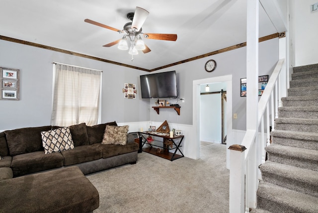 living room featuring a barn door, ceiling fan, crown molding, and light carpet