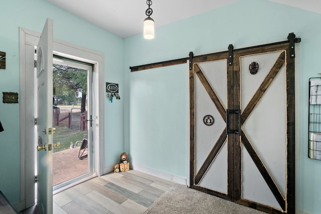 foyer entrance with a barn door and light wood-type flooring