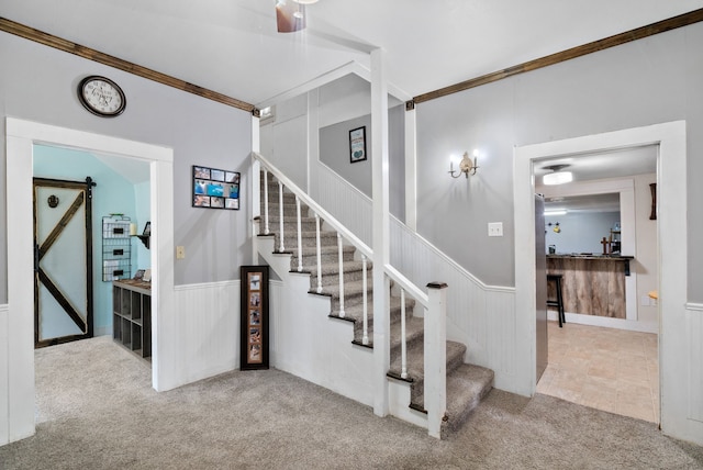 staircase with carpet, a barn door, and crown molding