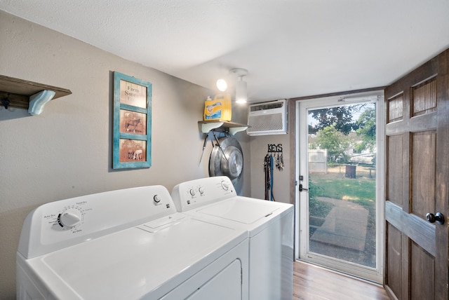 laundry room with washing machine and dryer, light hardwood / wood-style floors, and an AC wall unit