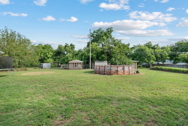 view of yard featuring a trampoline, a shed, and a swimming pool